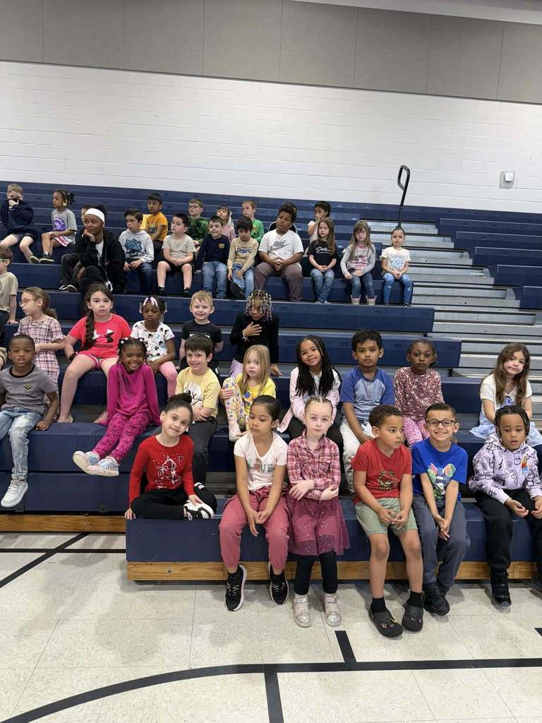 Students sitting on bleachers in their school gym. 