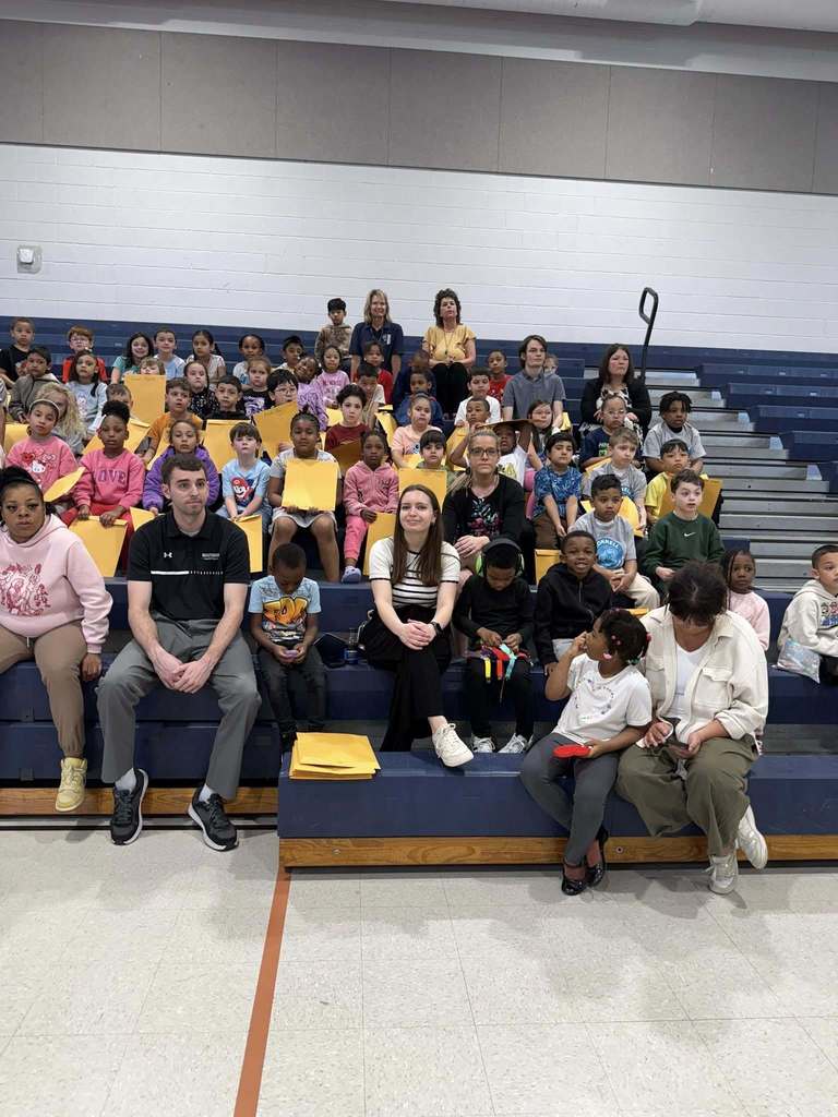 Students sitting on bleachers in their school gym. 