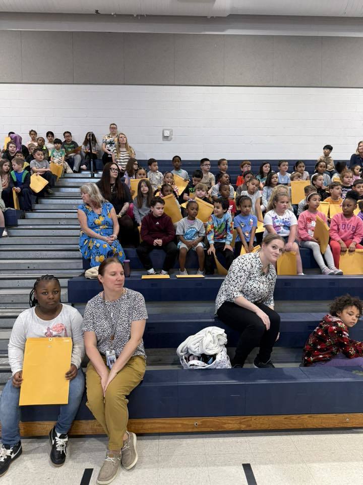 Students sitting on bleachers in their school gym. 