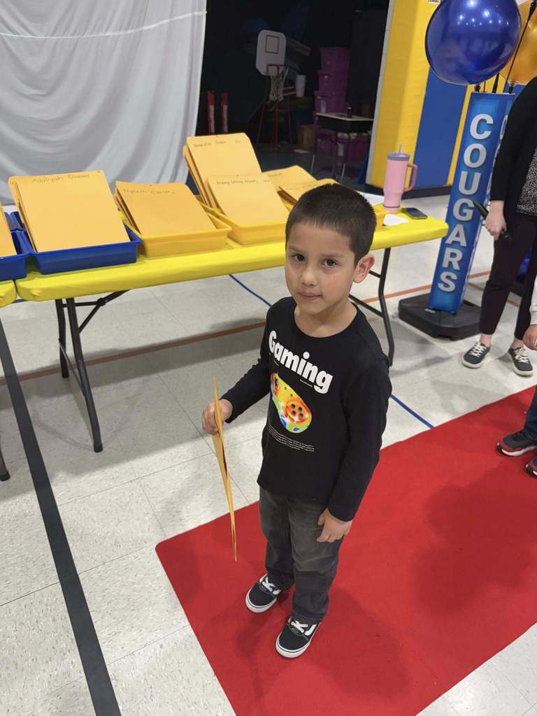 A student posing while he holds an envelope in his hand that contains his certificate. 