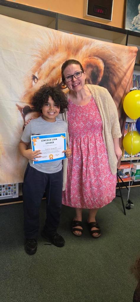 A student and principal, Carol Jo Huffman, posing while the student holds their Lincoln Lion Leaders Award. 