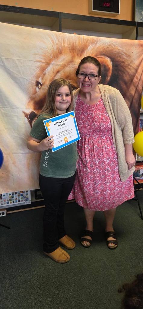 A student and principal, Carol Jo Huffman, posing while the student holds their Lincoln Lion Leaders Award. 
