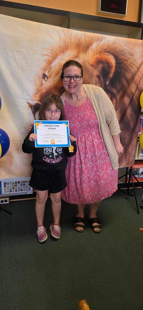 A student and principal, Carol Jo Huffman, posing while the student holds their Lincoln Lion Leaders Award. 