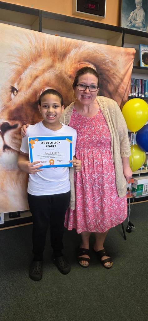 A student and principal, Carol Jo Huffman, posing while the student holds their Lincoln Lion Leaders Award. 