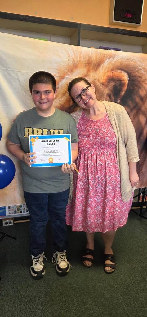A student and principal, Carol Jo Huffman, posing while the student holds their Lincoln Lion Leaders Award. 