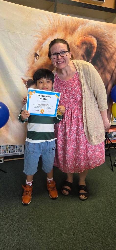 A student and principal, Carol Jo Huffman, posing while the student holds their Lincoln Lion Leaders Award. 