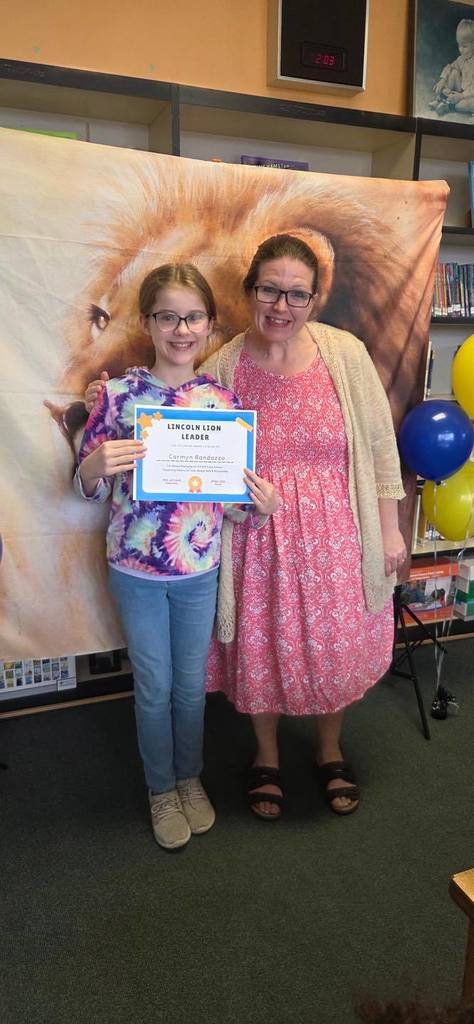 A student and principal, Carol Jo Huffman, posing while the student holds their Lincoln Lion Leaders Award. 