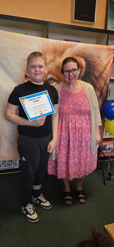 A student and principal, Carol Jo Huffman, posing while the student holds their Lincoln Lion Leaders Award. 
