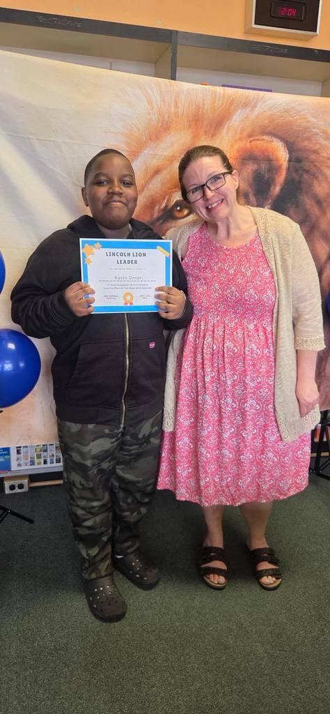 A student and principal, Carol Jo Huffman, posing while the student holds their Lincoln Lion Leaders Award. 