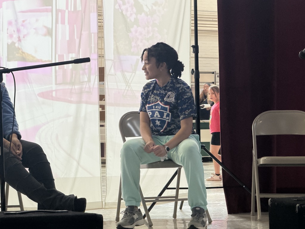 Students acting on stage while sitting. 