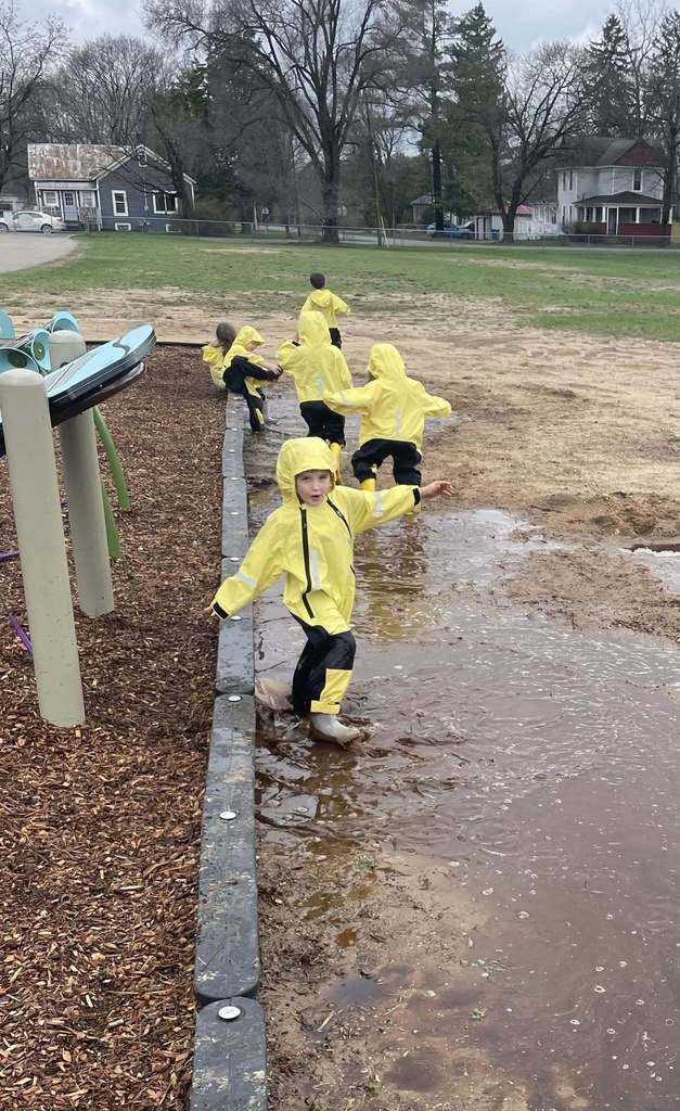 Preschool students playing in mud puddles
