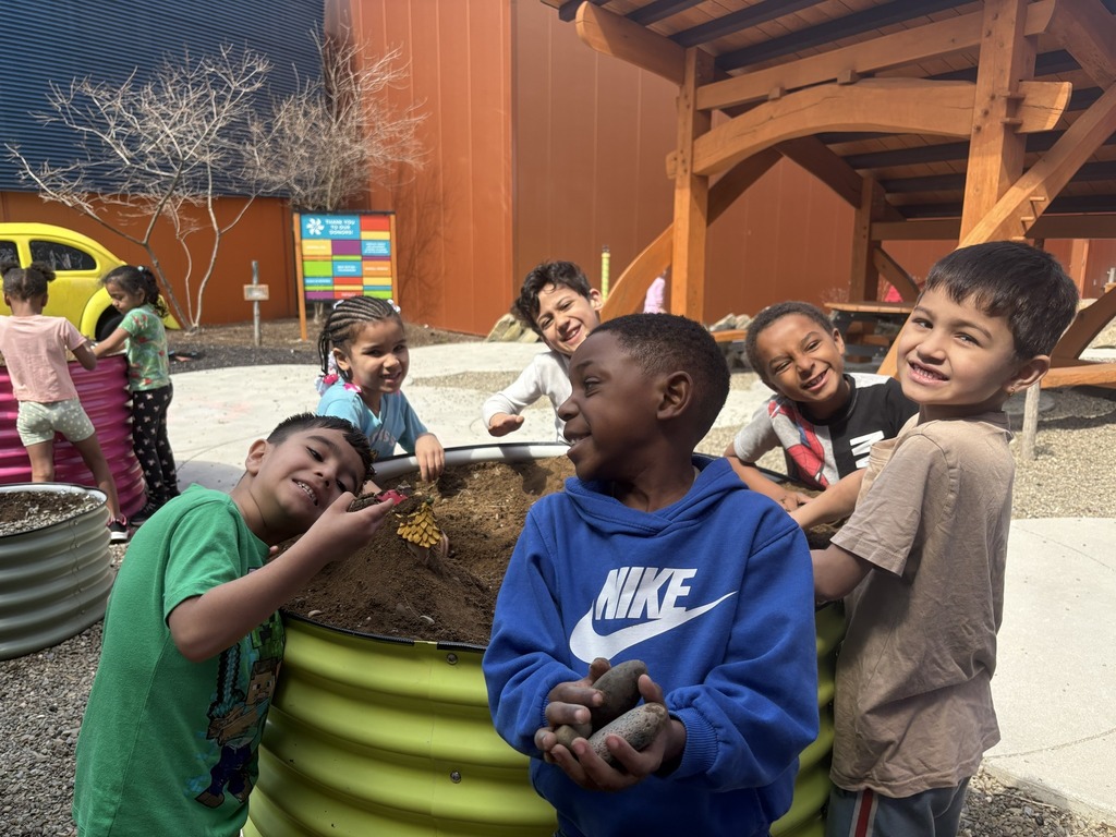 Kids posing around a dirt play area. 
