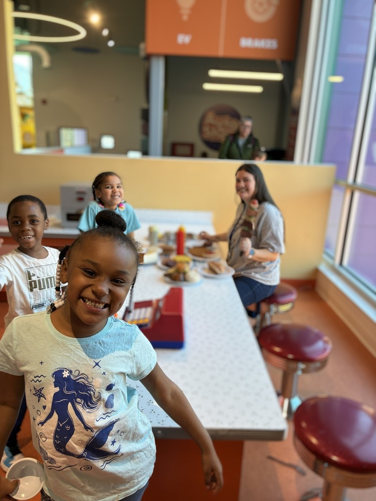 Students posing at a long table with stools.