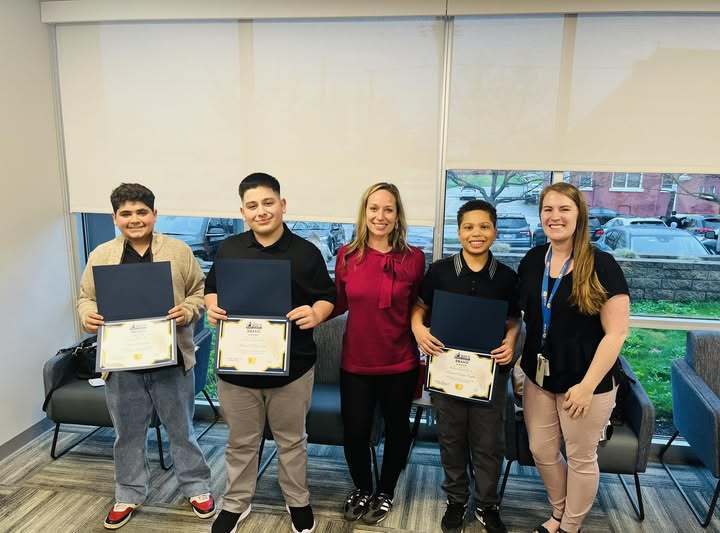 Students holding their Bravo awards while standing next to staff.