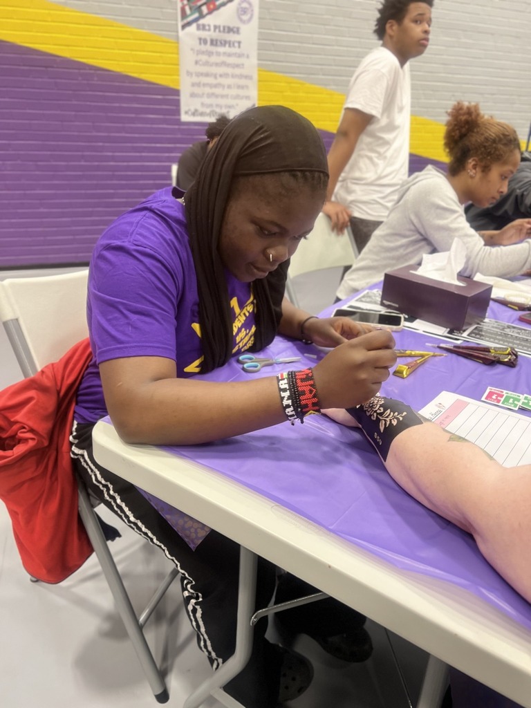 A student doing a henna on someone's hand. 