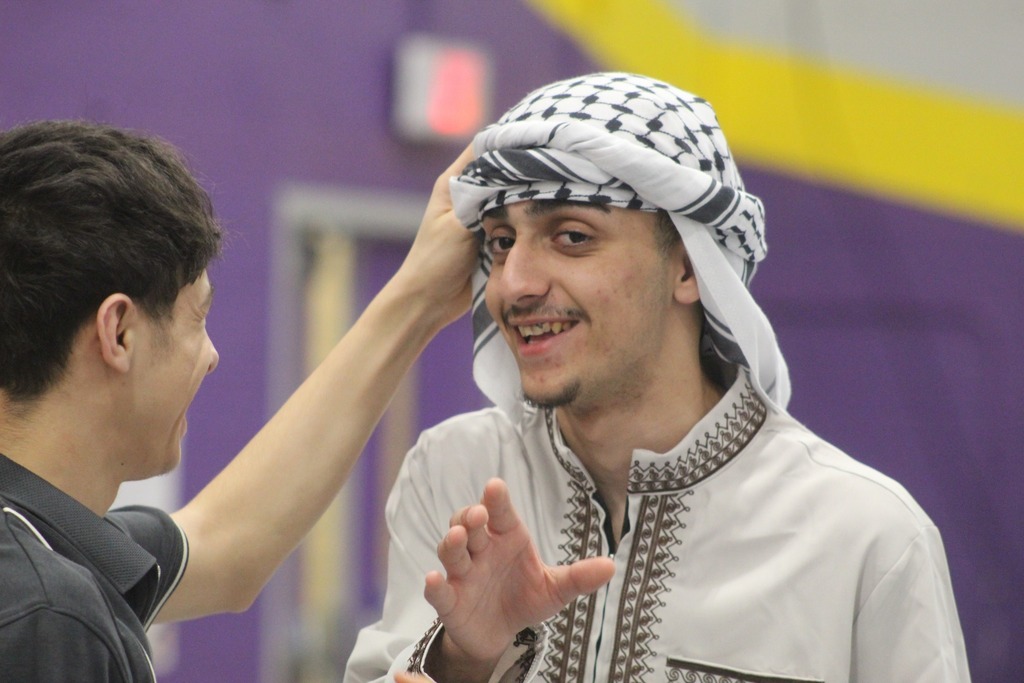 A young man dressed in cultural wear and is smiling. 
