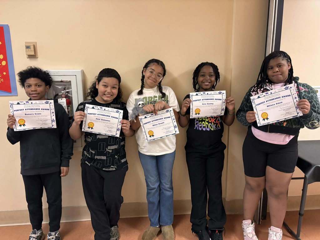Students posing while they hold their perfect attendance awards. 