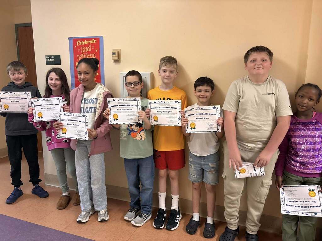 Students posing while they hold their perfect attendance awards. 