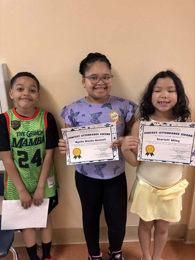 Students posing while they hold their perfect attendance awards. 