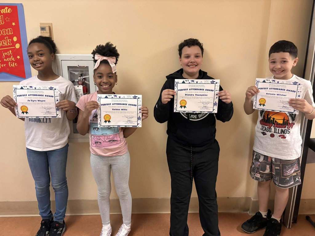 Students posing while they hold their perfect attendance awards. 