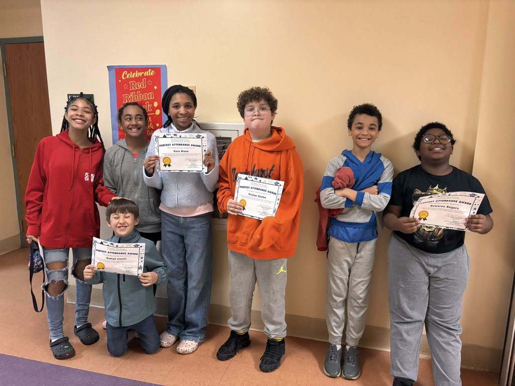Students posing while they hold their perfect attendance awards. 