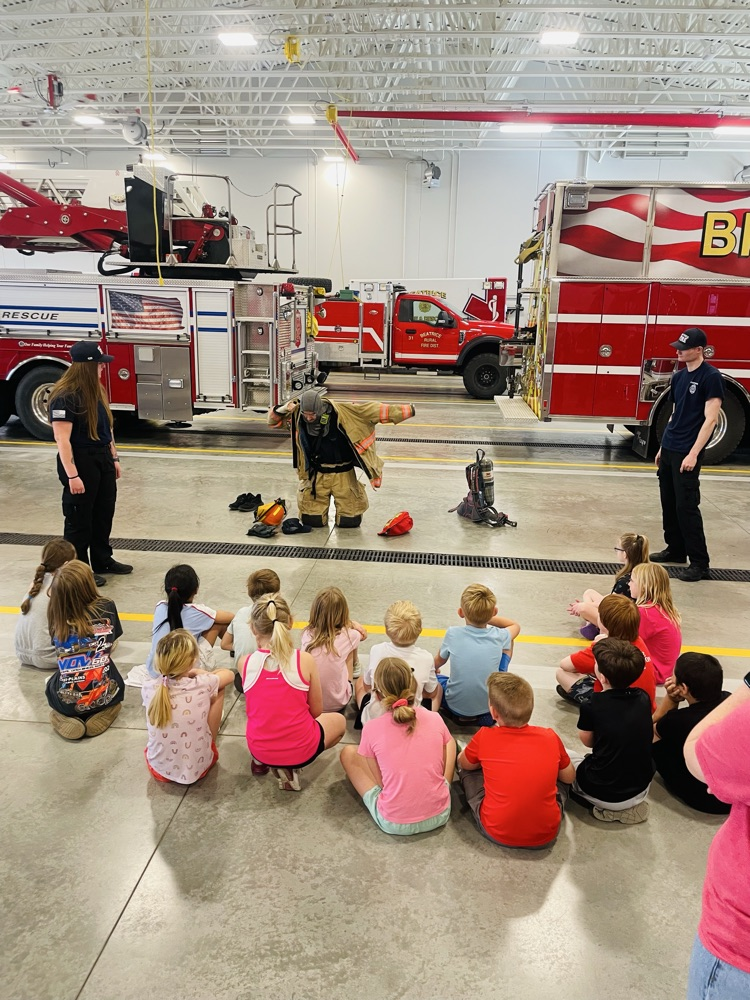 first graders watching a firefighter put his gear on 