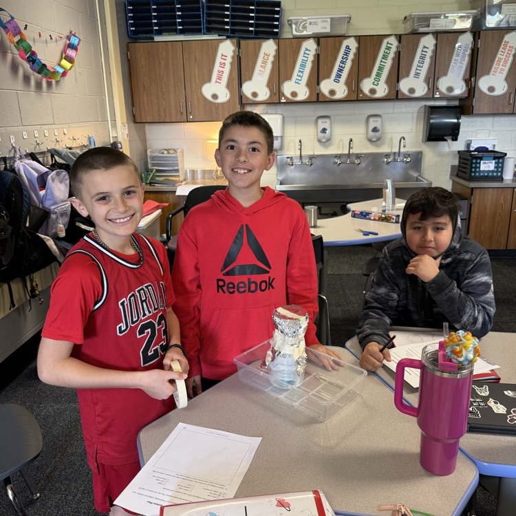 Three students showing their water filtration system