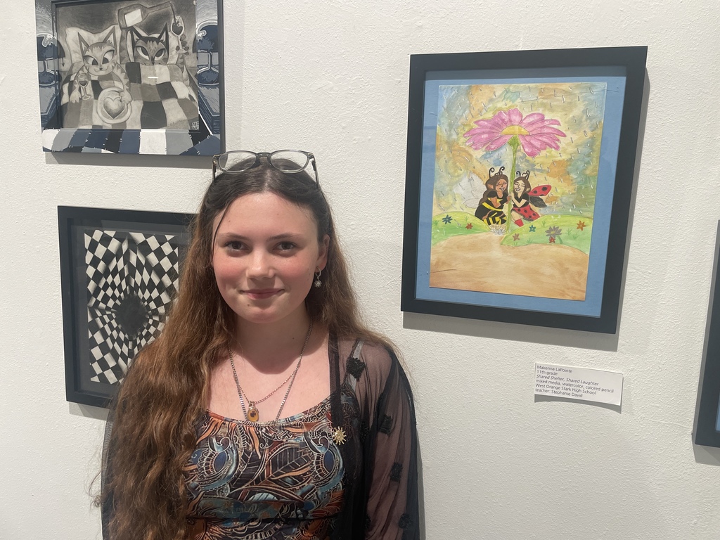 students standing with her work in an art exhibit