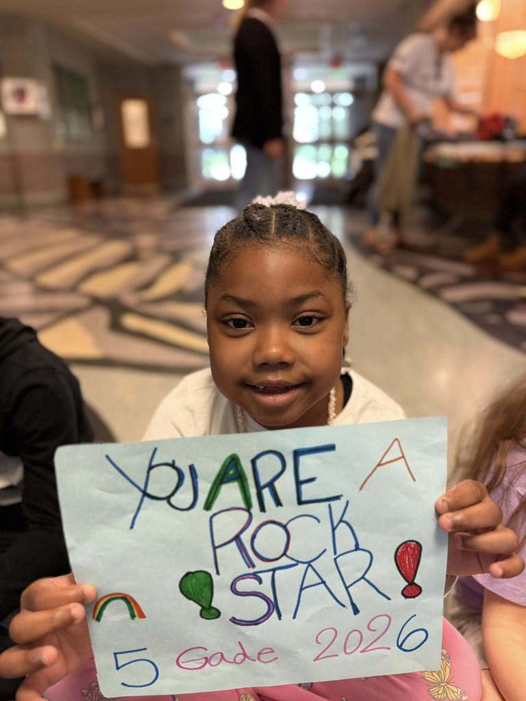 Students standing with posters they made to wish students good luck in their school.