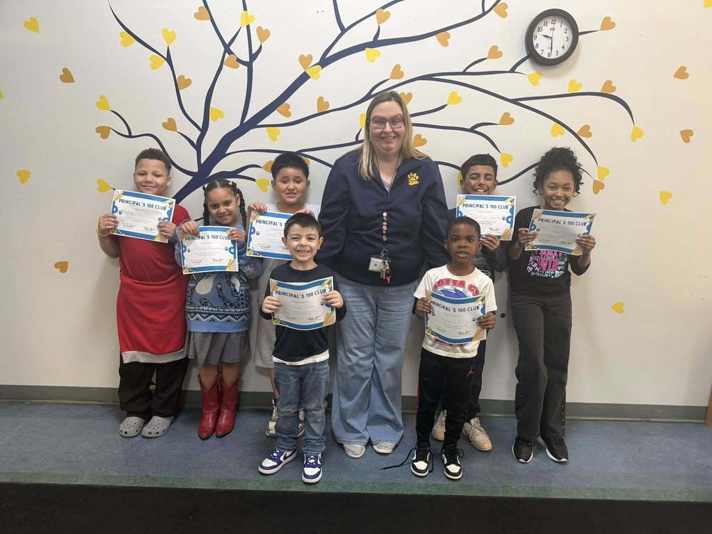 A teacher and students holding their Principal 100 Club awards. 
