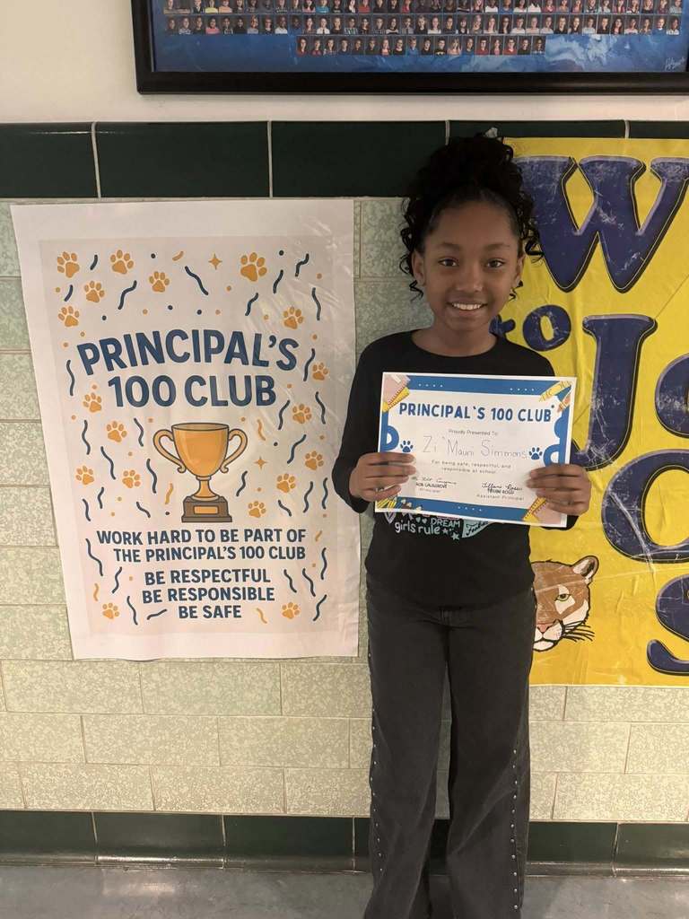 A student holding his Principal 100 Club award. 