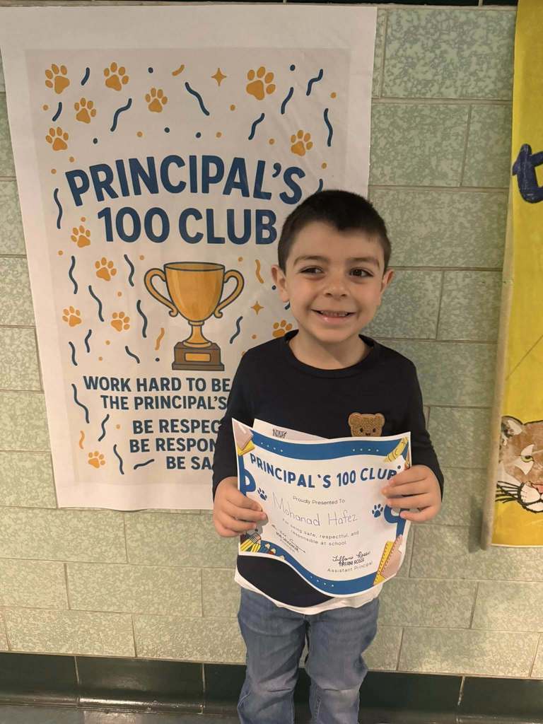 A student holding his Principal 100 Club award. 