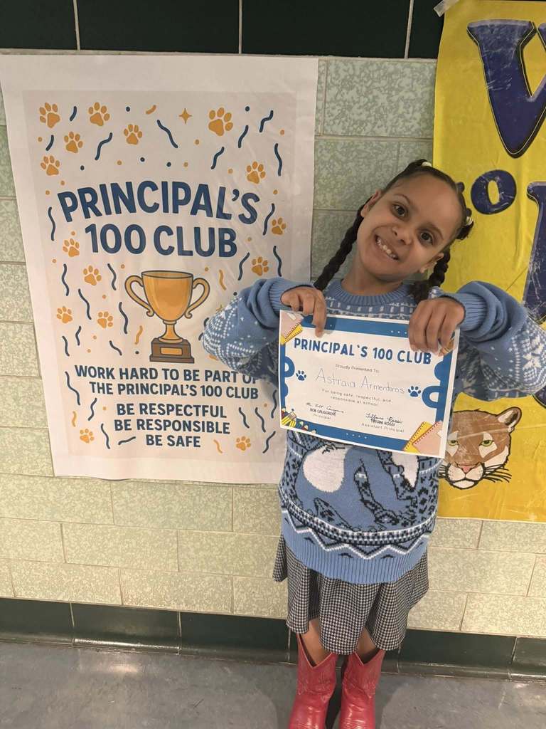 A student holding his Principal 100 Club award. 