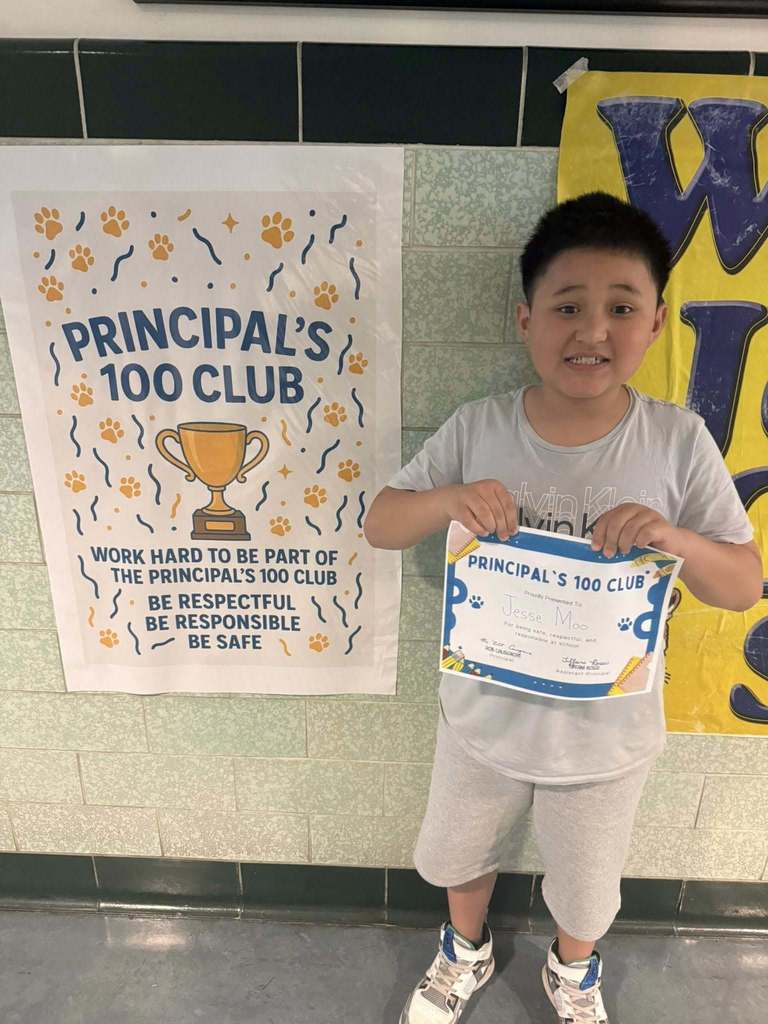 A student holding his Principal 100 Club award. 