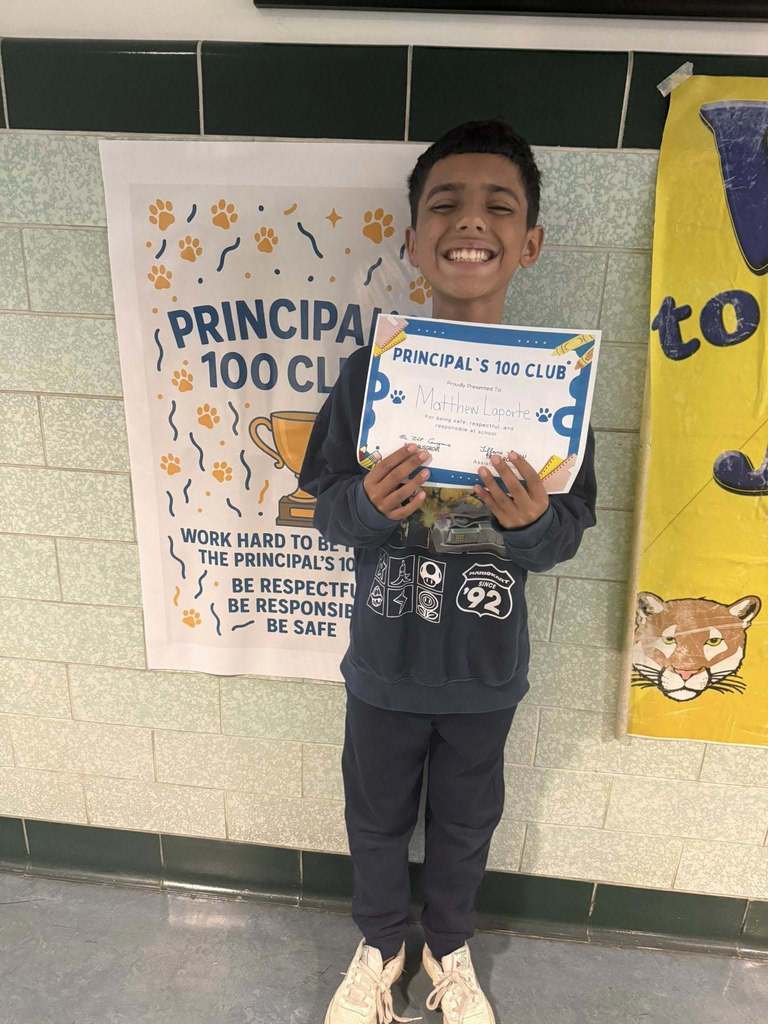 A student holding his Principal 100 Club award. 