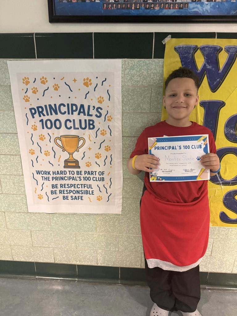 A student holding his Principal 100 Club award. 