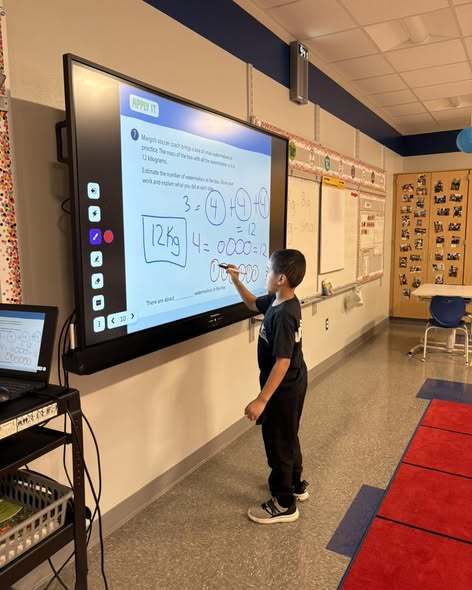 A student writing on a new projector board. 
