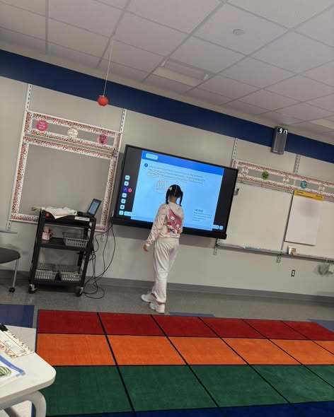 A student writing on a new projector board. 