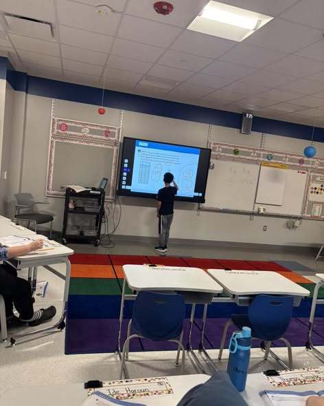 A student writing on a new projector board. 
