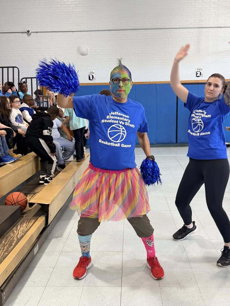 A man wearing a tutu and has green and blue face paint on is dancing. 