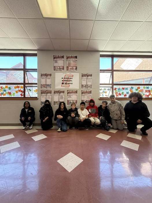 Students kneeling in the hall and posing. 