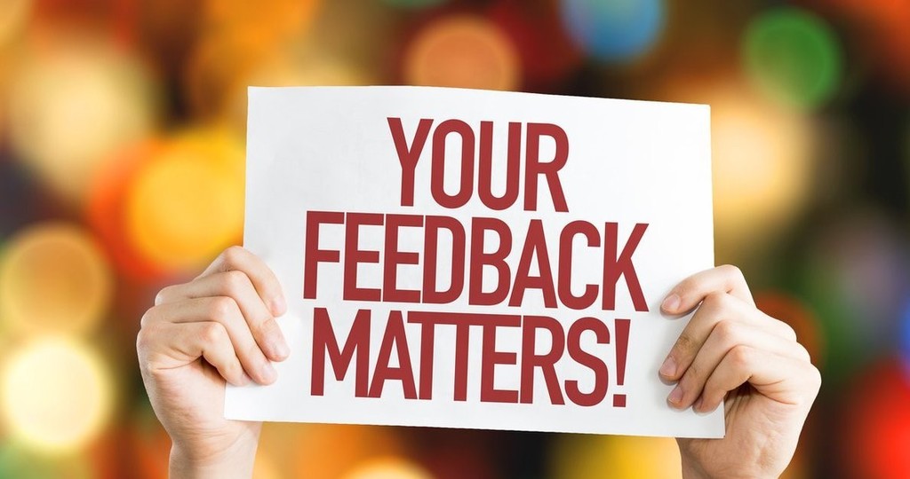 Person holding a sign that says your feedback matters.