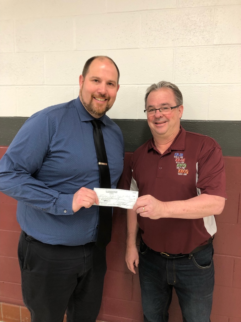 Principal taking donation check from radio announcer.