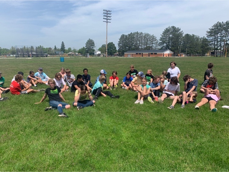 children sitting on the grass receiving awards