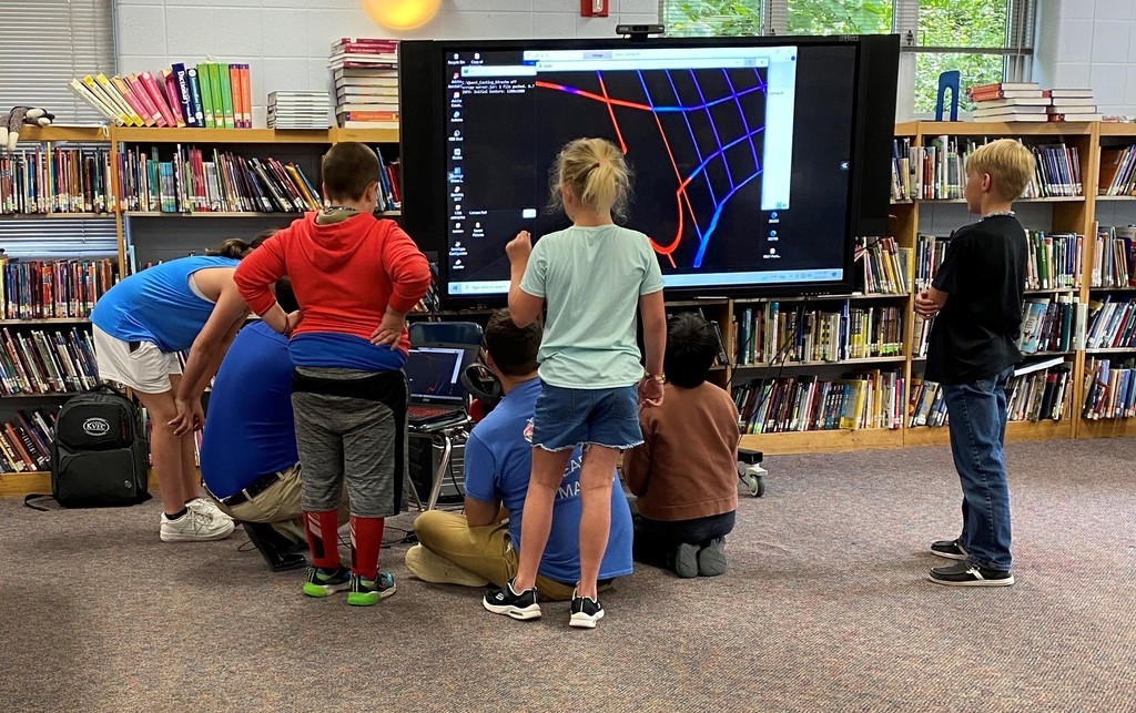 Students looking on as staff setup virtual reality equipment