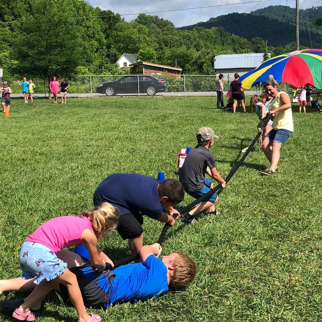 students playing tug o war outside falling down as other team pulls