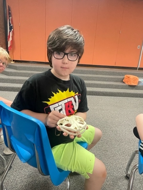 A boy at summer school holding an animal skull.