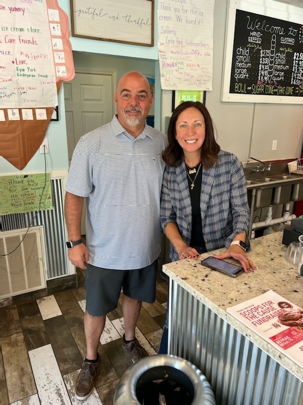 A man and a woman pose and smile standing at a counter