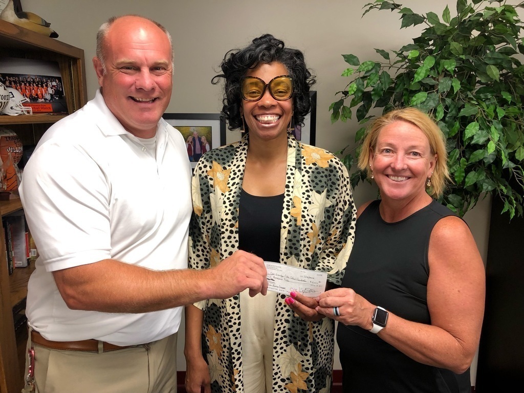 three people smile with a check donation