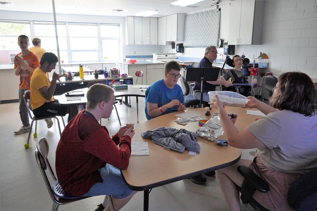 students at tables with teacher and aides